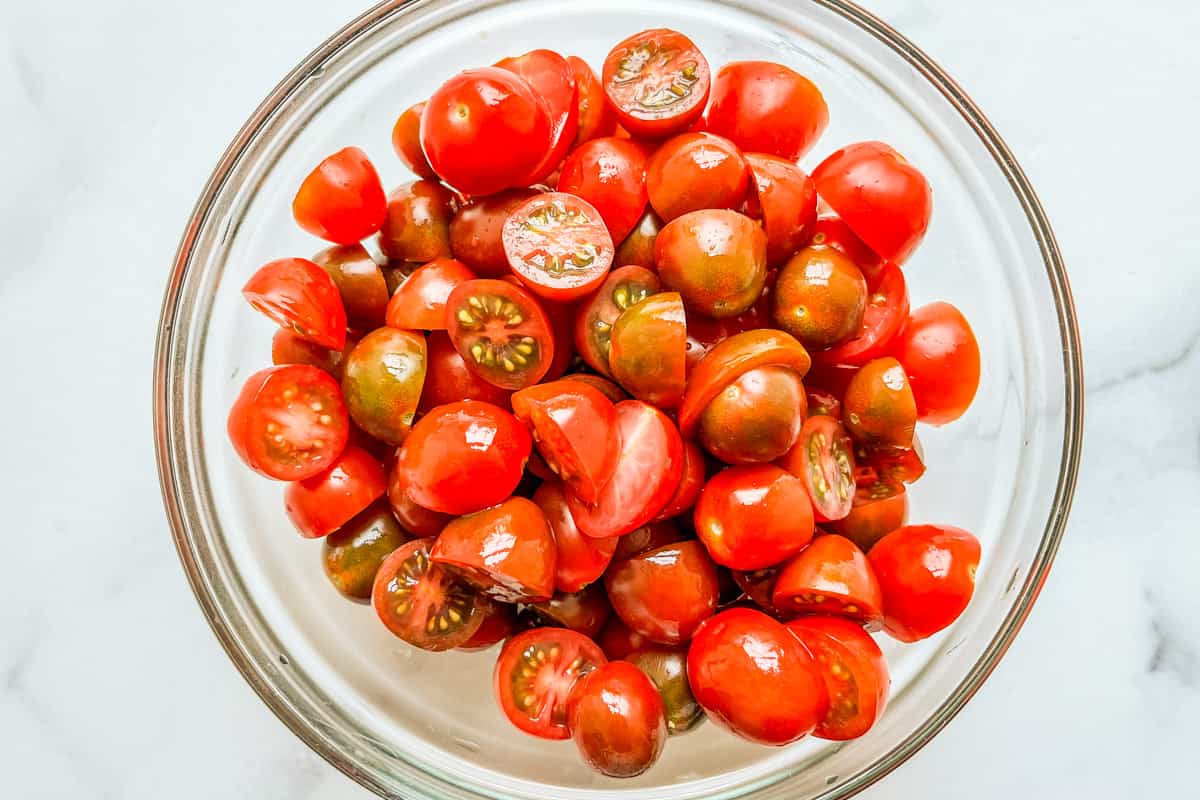 Sliced cherry tomatoes in a glass bowl.