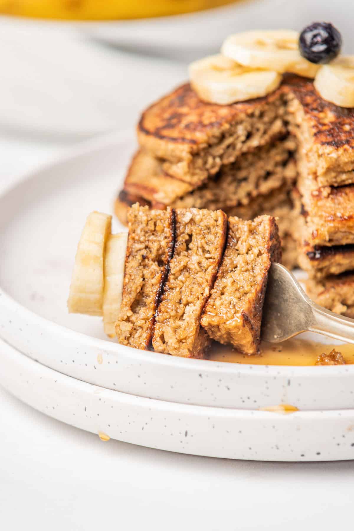 Banana oat pancakes in a stack on a white plate.