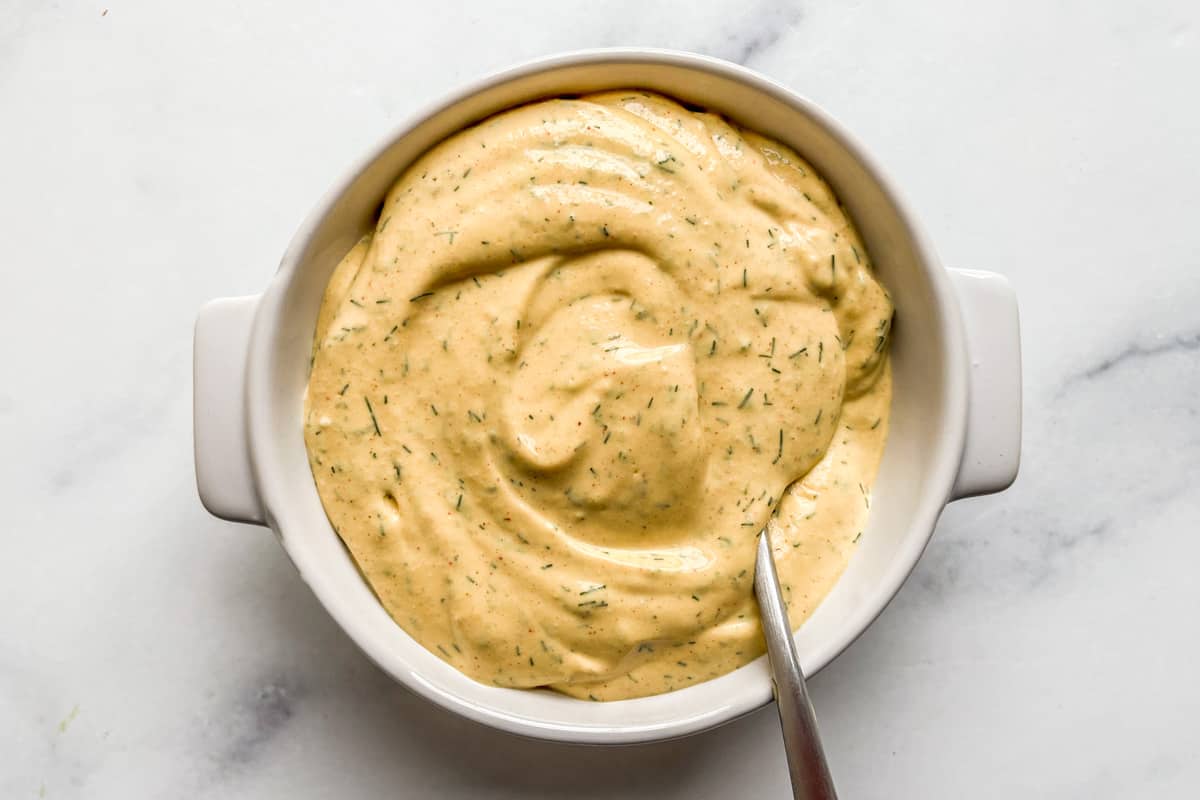 Mustard cottage cheese dip in a ramekin with a spoon.