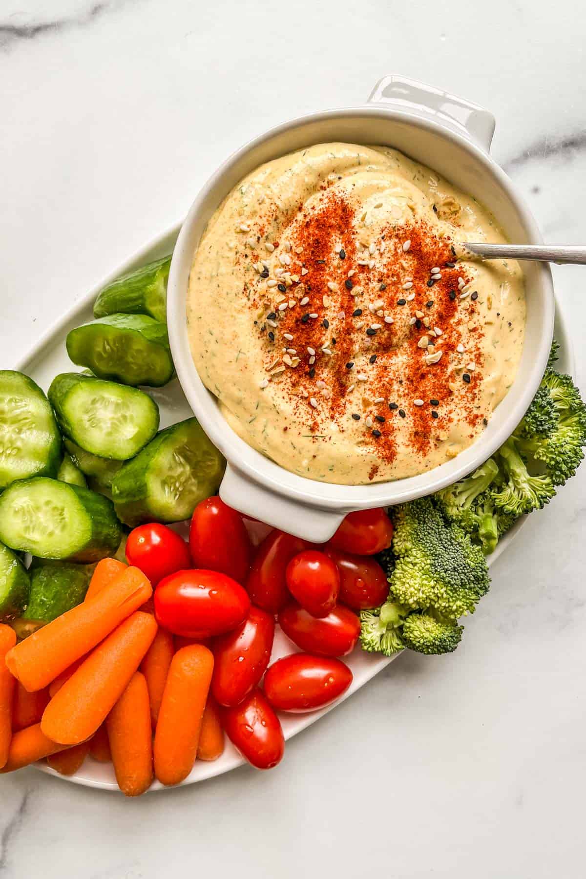 A mustard cottage cheese dip with fresh vegetables on a white platter.