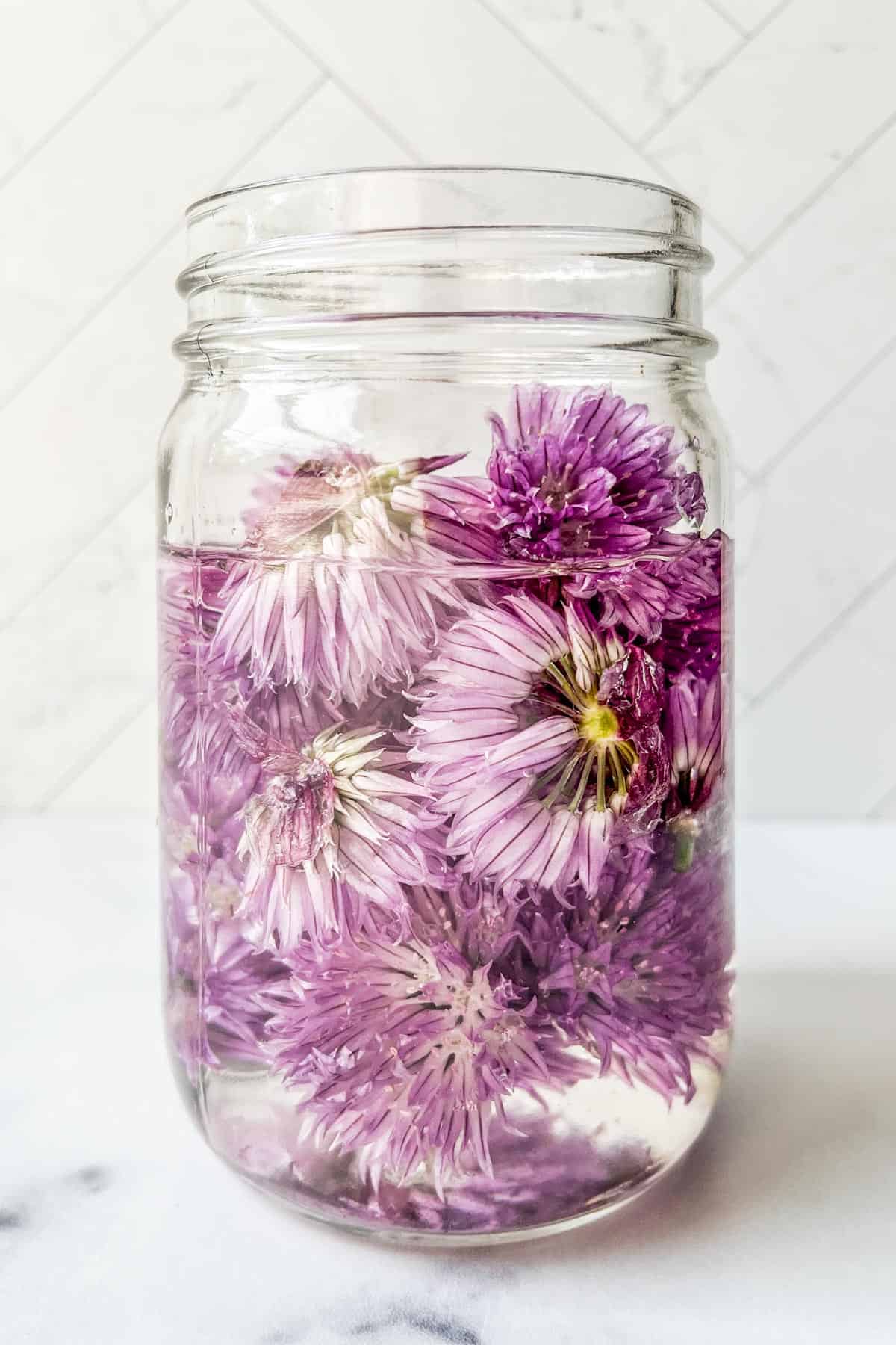 A jar with vinegar and chive blossoms.