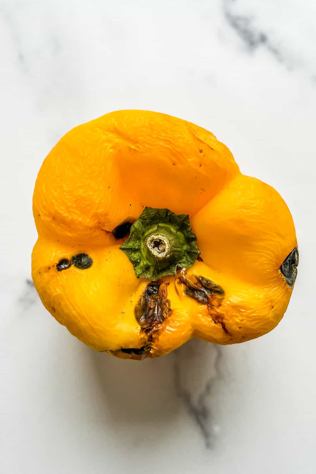 A yellow bell pepper with dark spots.