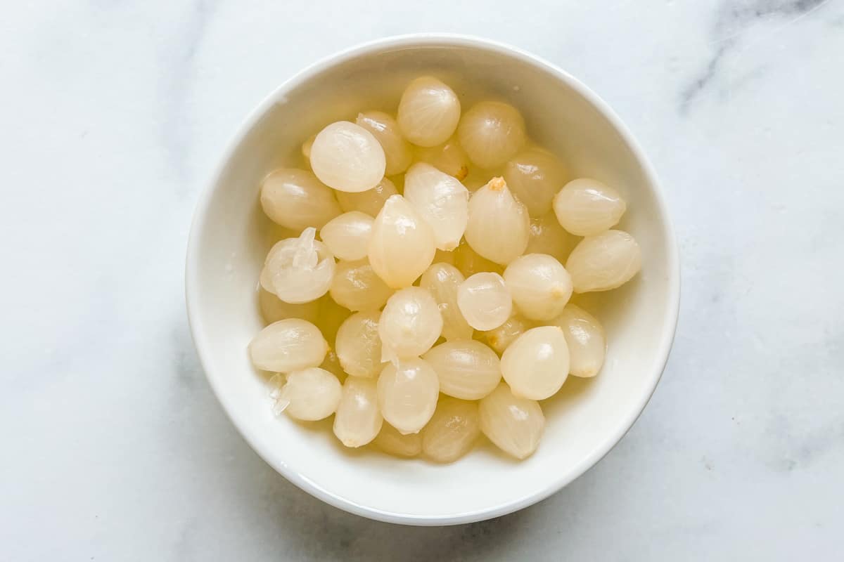 Pearl onions in a small white bowl.