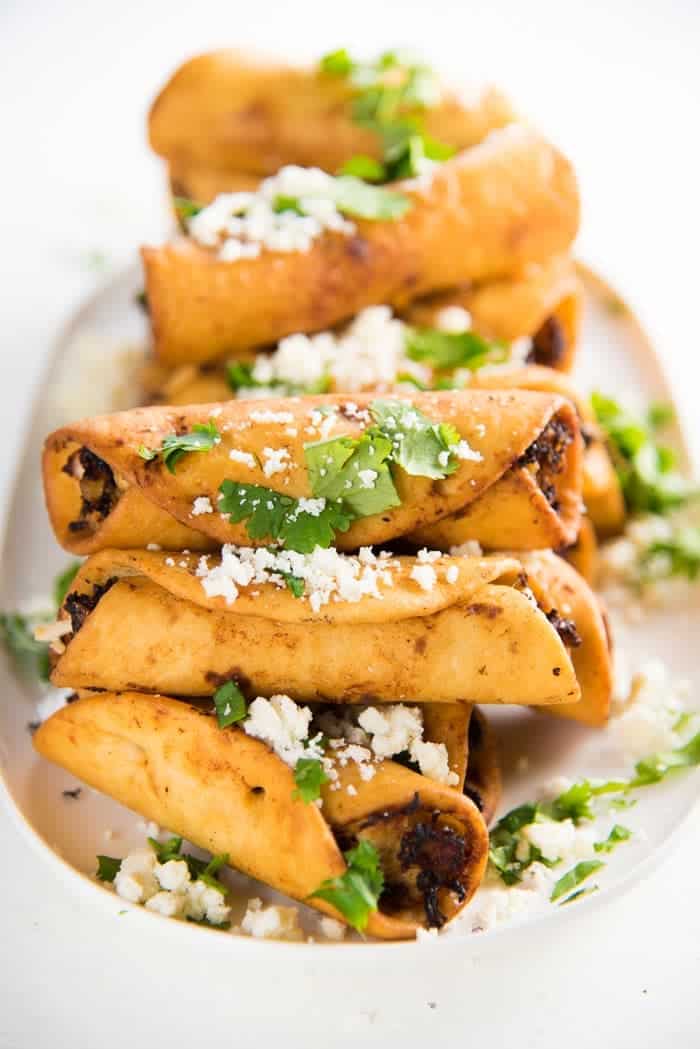 A stack of mini chicken taquitos on a plate.