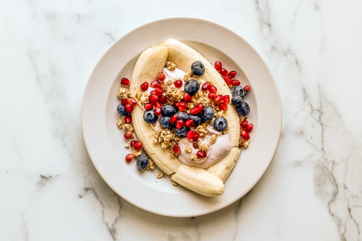 A healthy banana split on a white plate.