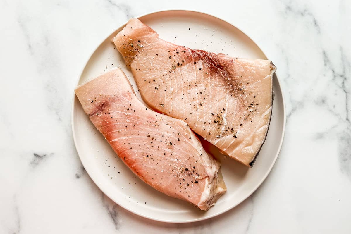 Swordfish steaks topped with salt and pepper.