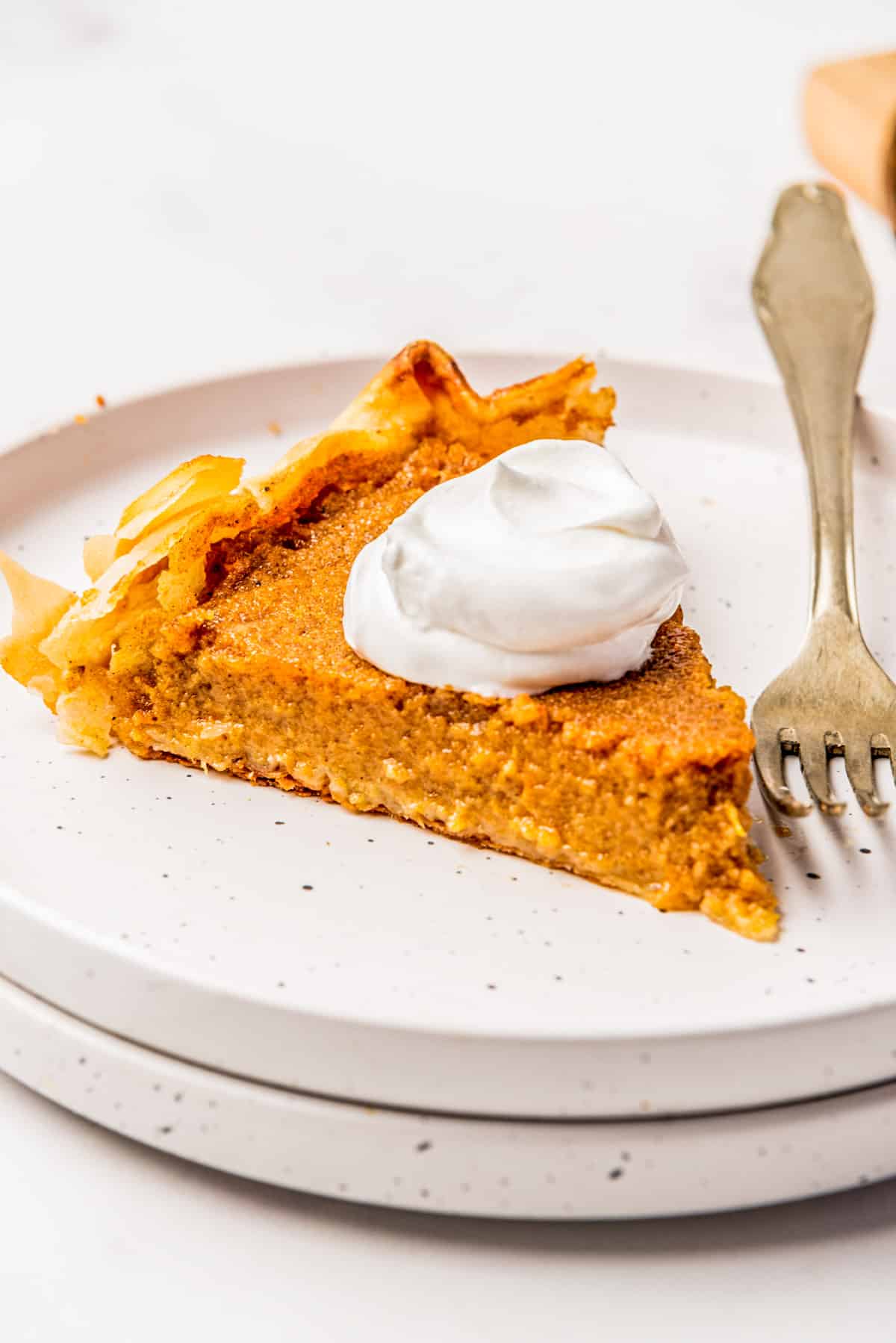A slice of sweet potato pie on a white plate with a fork.