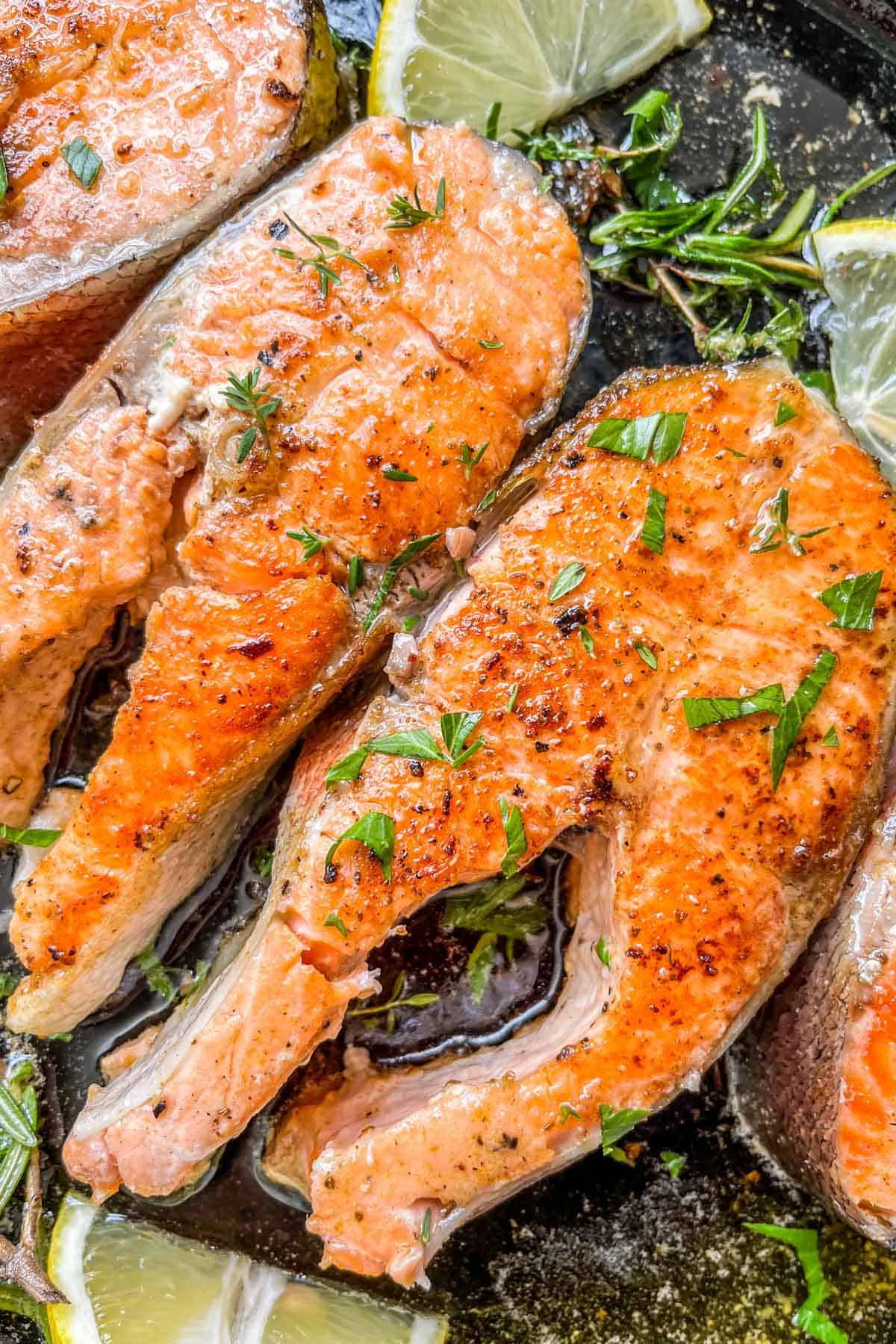 Lemon herb butter salmon steaks in a cast iron pan.