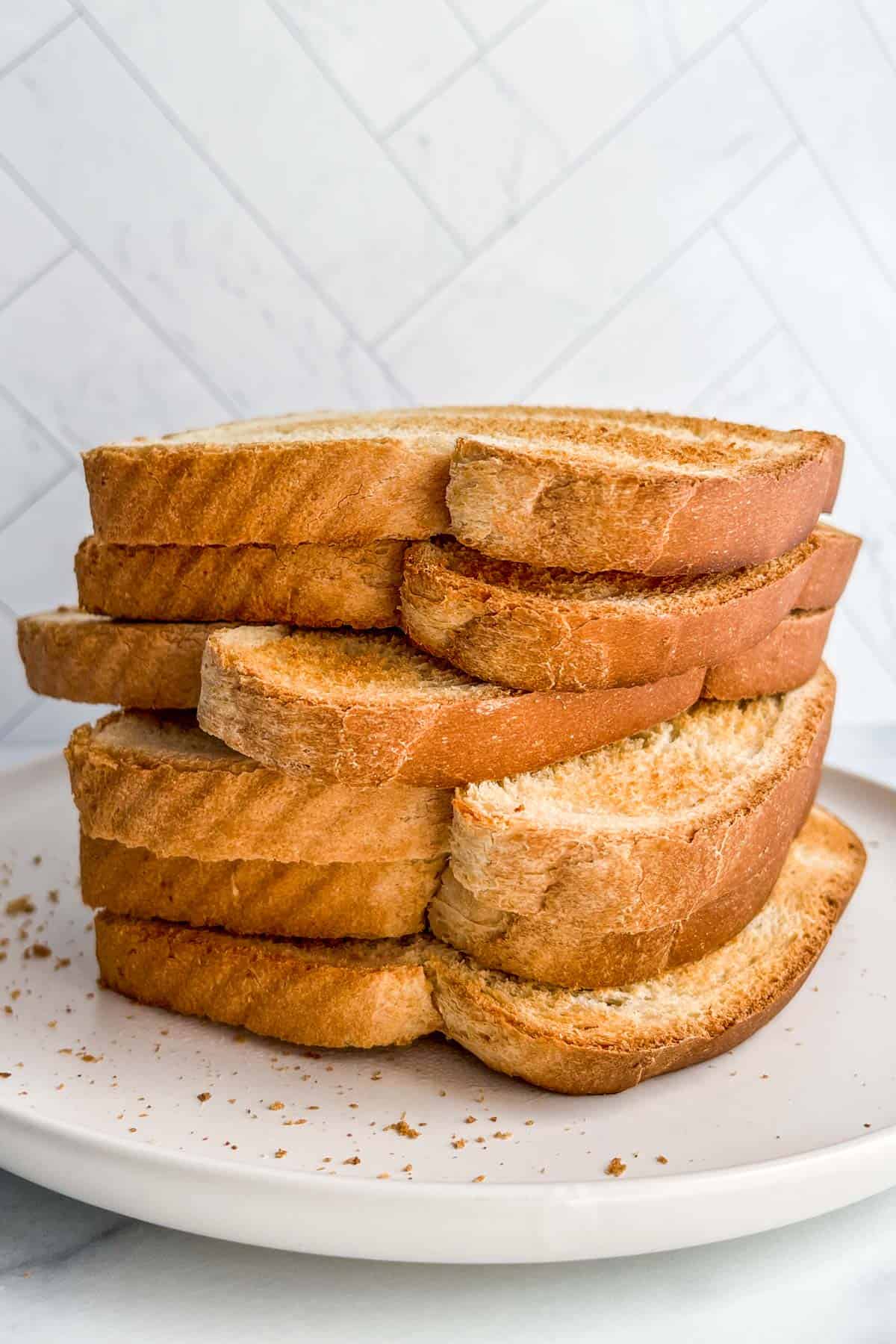 A stack of toasted bread on a white plate.