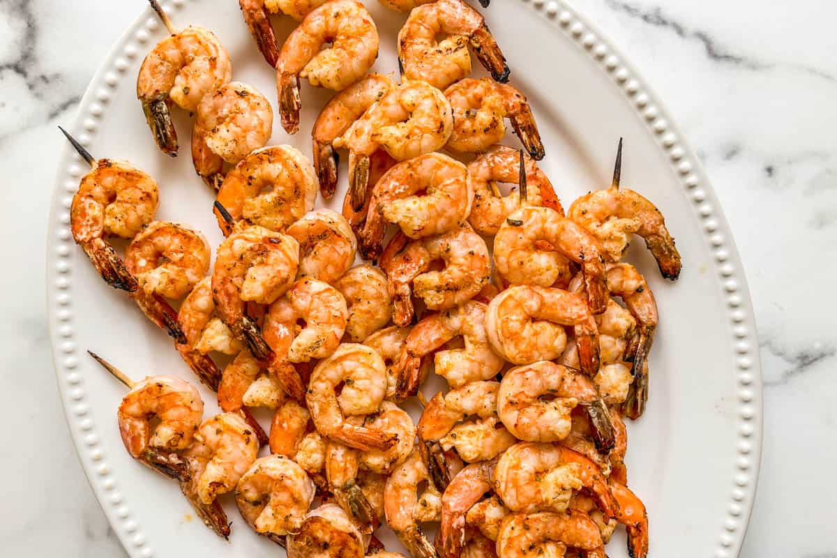 Grilled shrimp skewers on a large white platter.