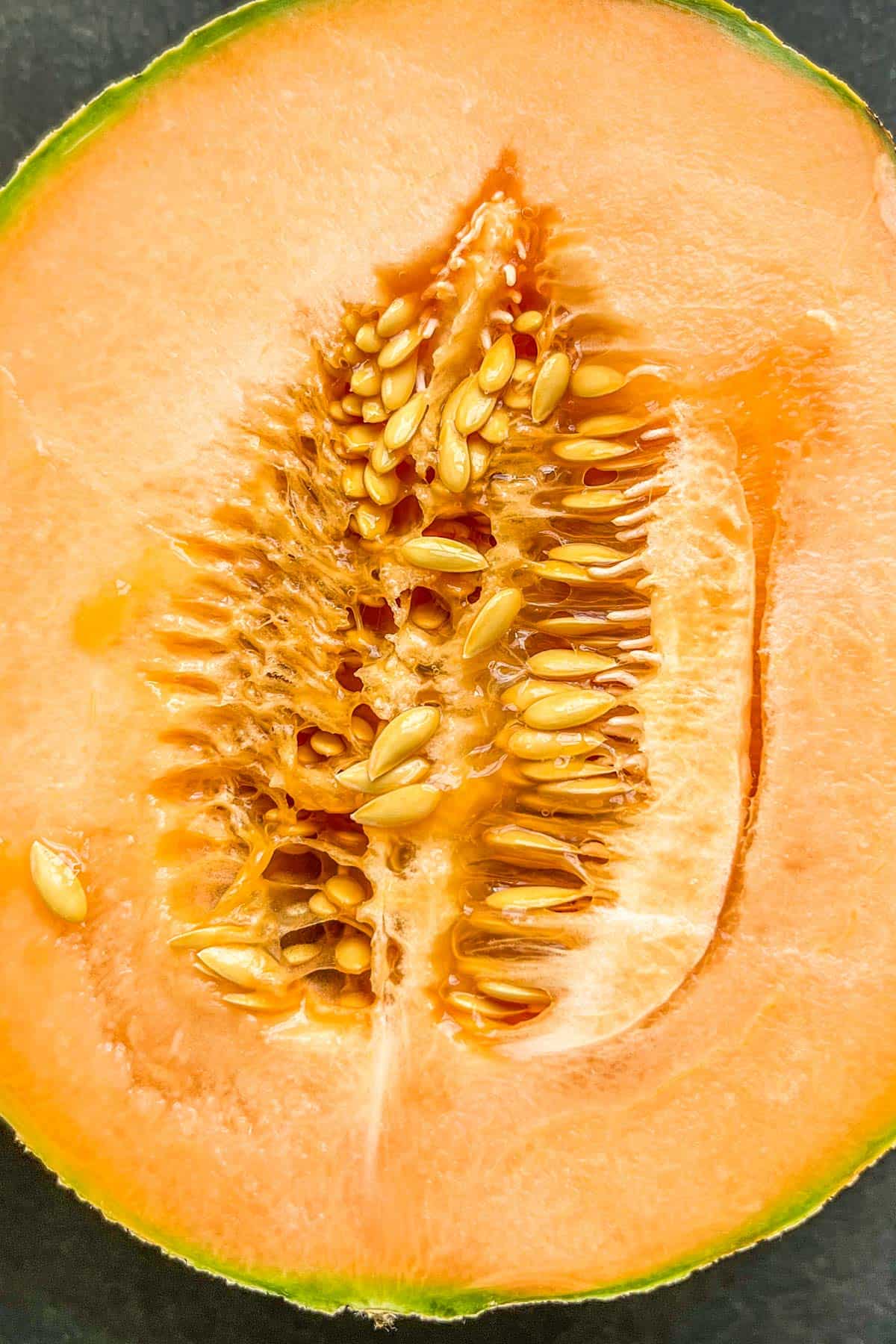 A halved cantaloupe with a gooey interior.