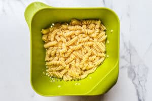 Cooked fussili pasta in a green colander.