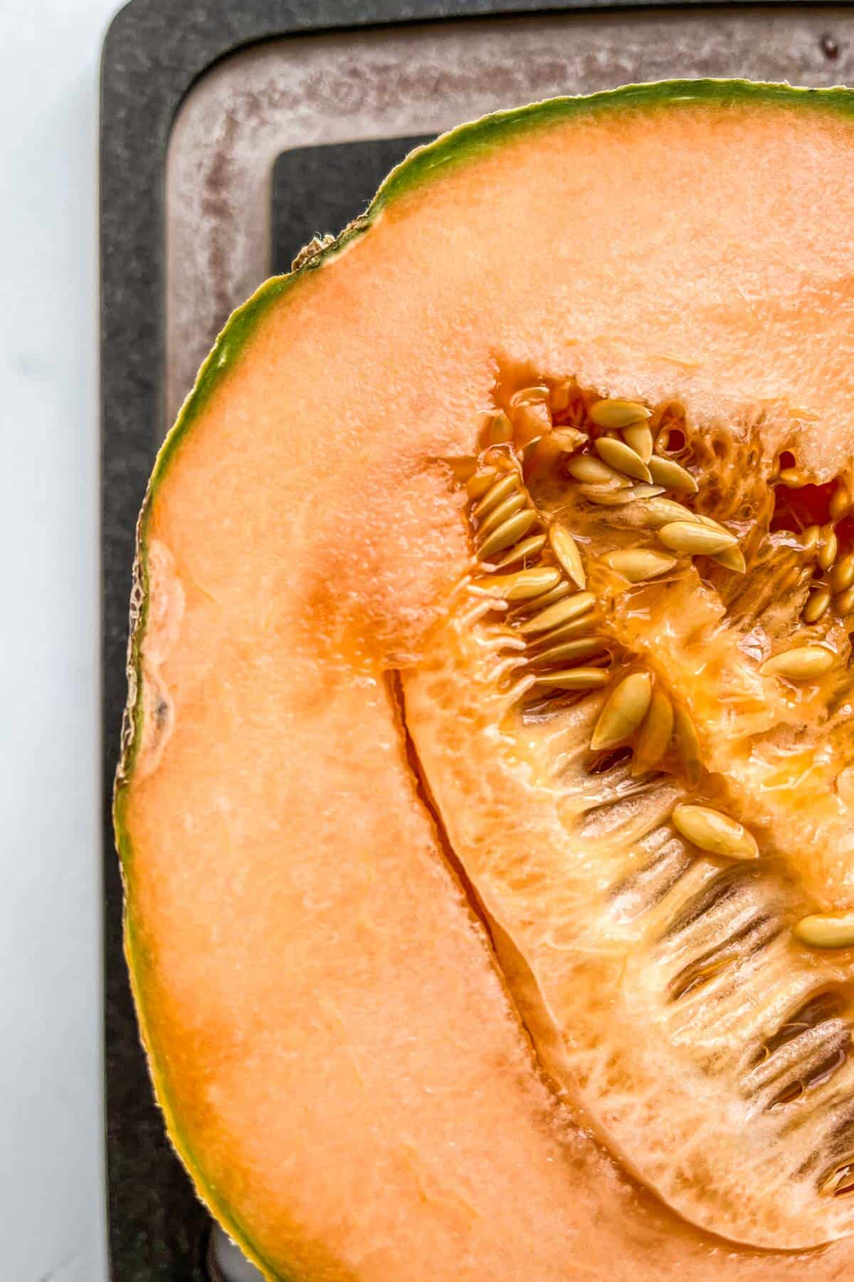 A halved cantaloupe with mold on the edge.