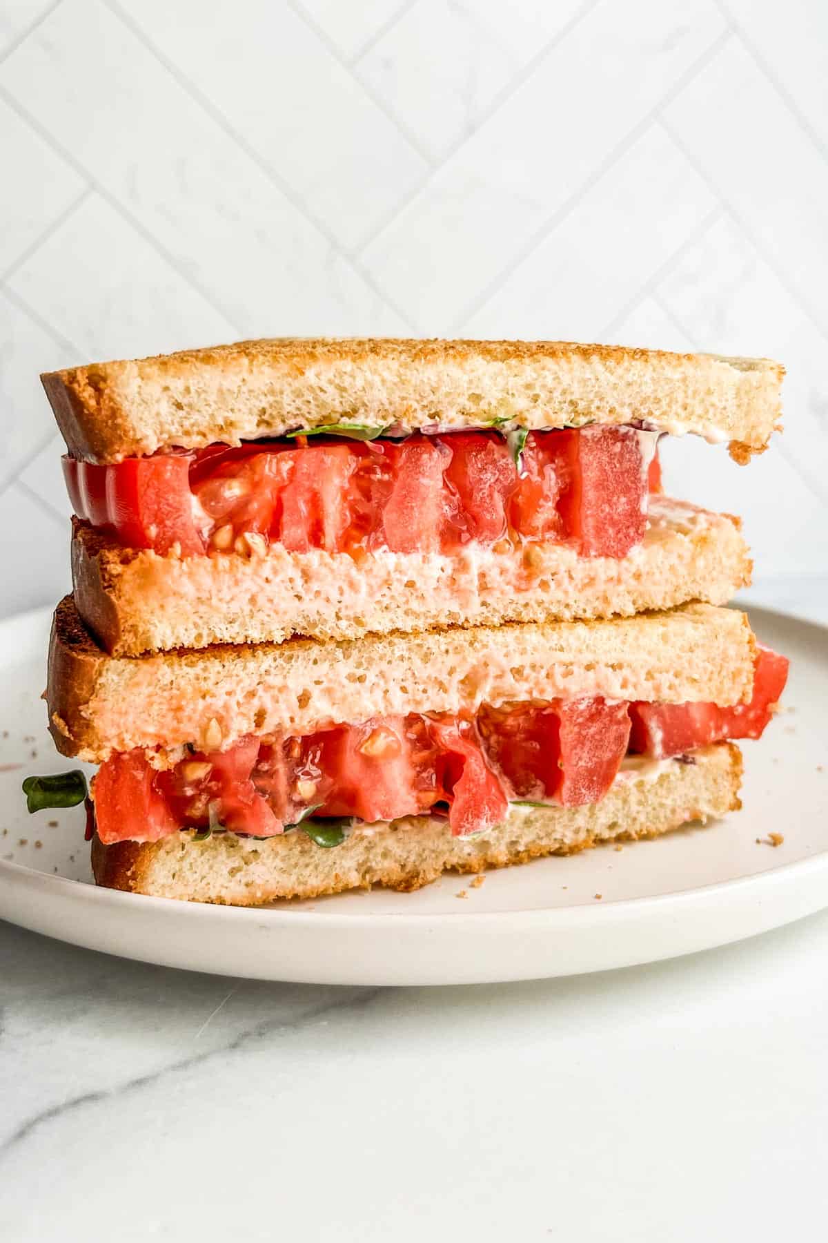 A tomato sandwich on a white plate.