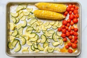 Roasted sweet corn, tomatoes, and summer squash on a sheet pan.