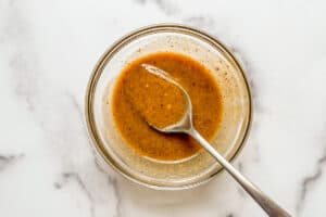 Vegan caramel sauce in a small glass bowl with a spoon.