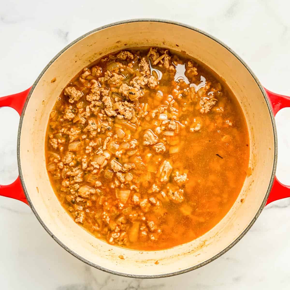 Stock added to browned ground turkey, onions, and spices in a pot.