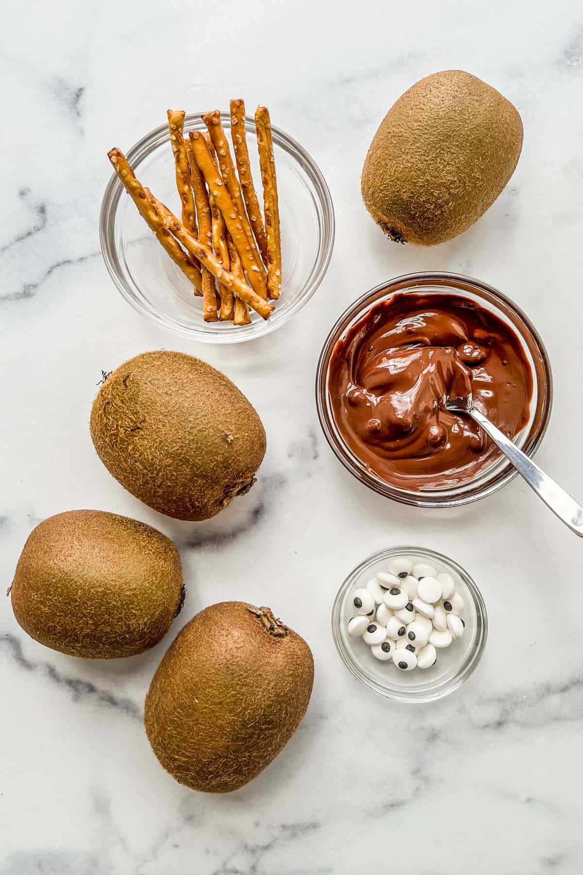 Pretzel sticks, kiwis, melted chocolate, and candy eyes.