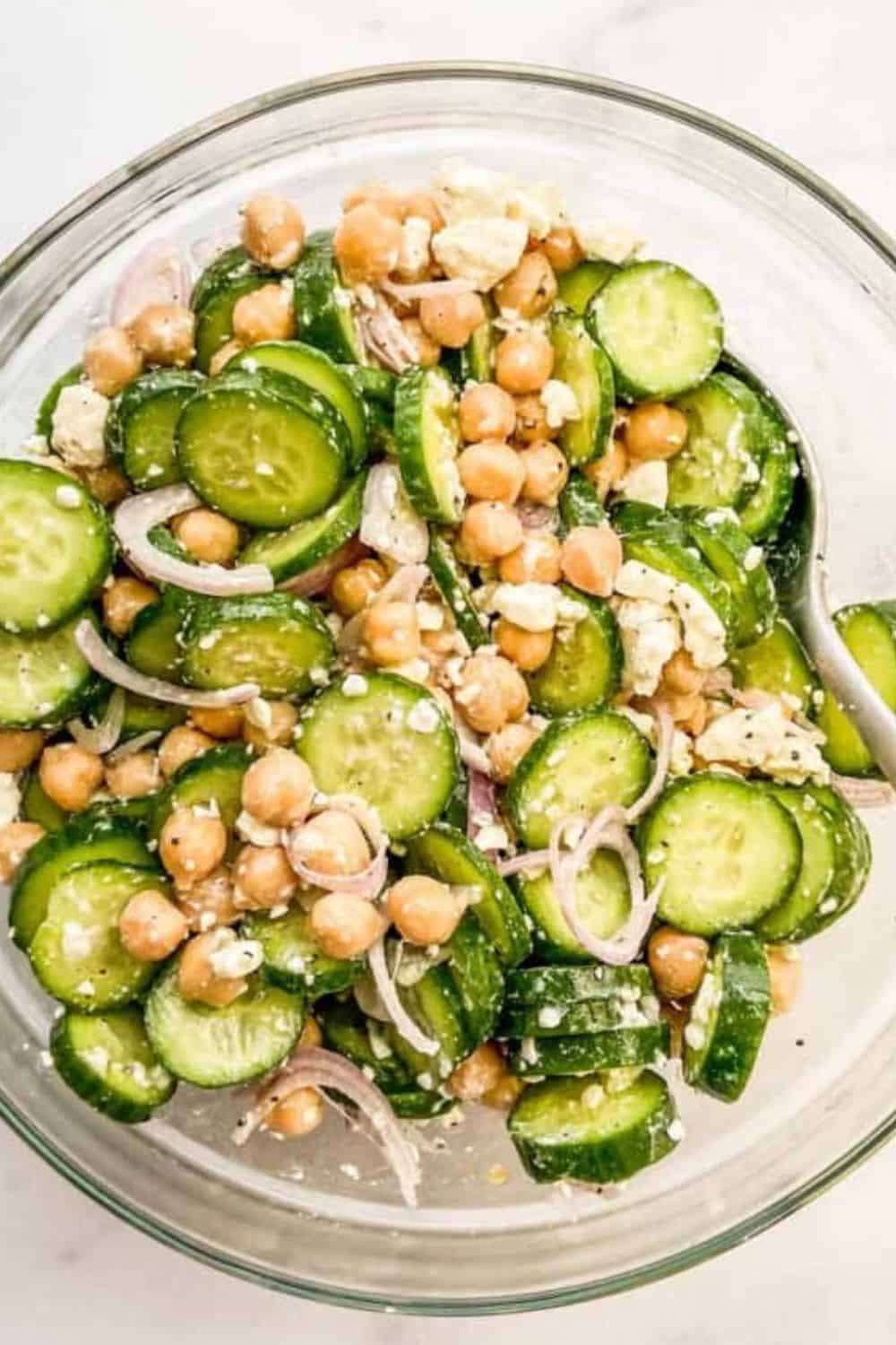 A cucumber chickpea salad in a glass bowl.