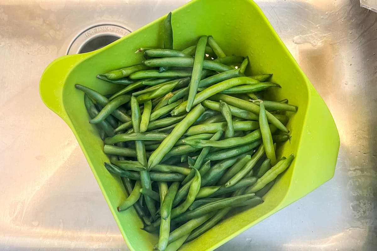 Draining fresh green beans in a strainer.