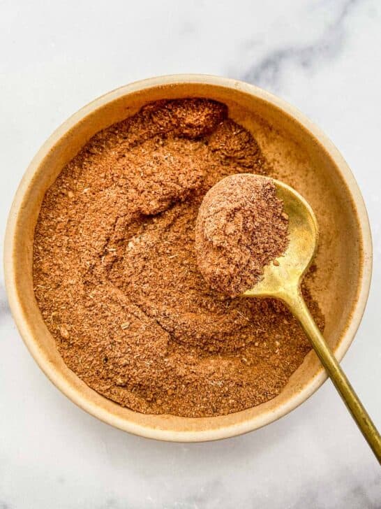 Chai spice blend in a bowl with a gold spoon.