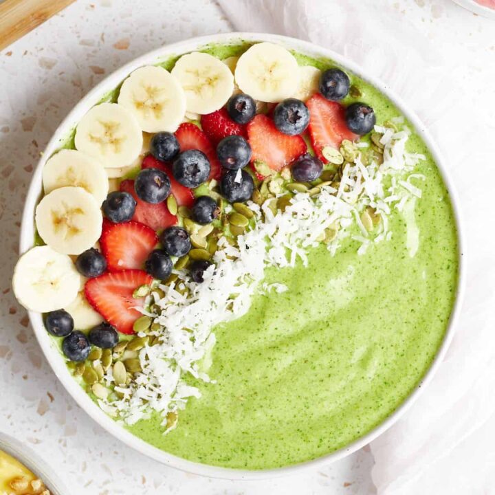 A green smoothie bowl with banana, berry, and coconut flake toppings.