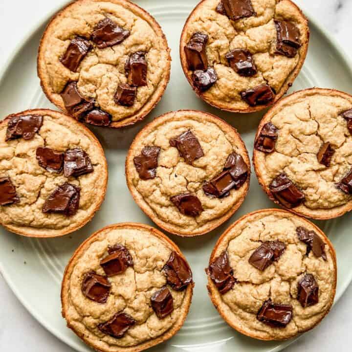 Banana oat muffins with chocolate chunks on a green plate.