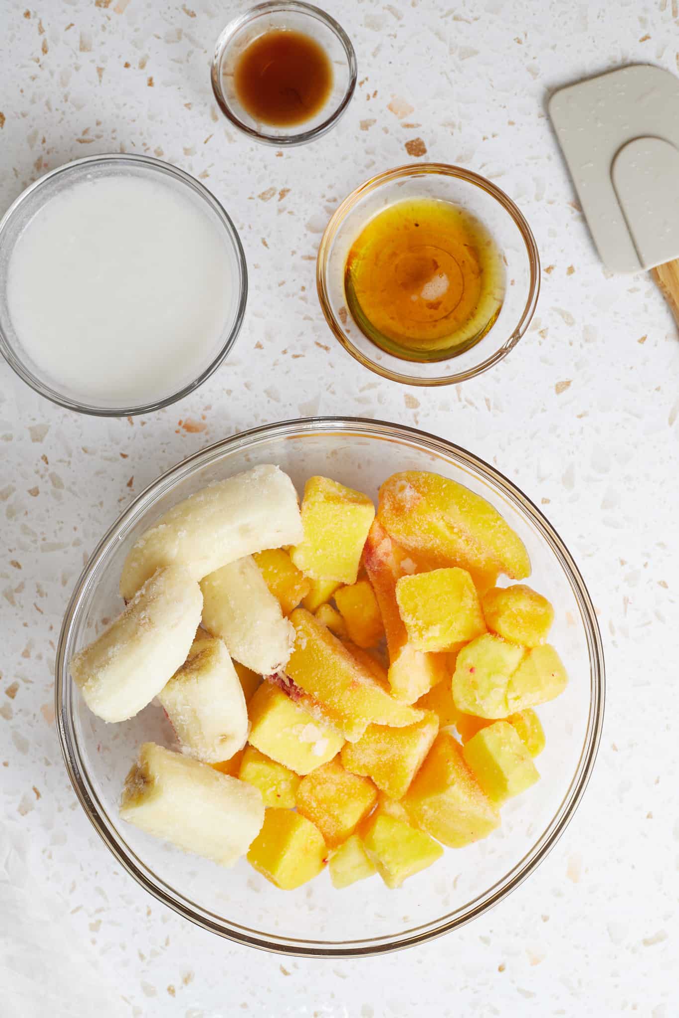 Ingredients for a mango peach smoothie bowl.