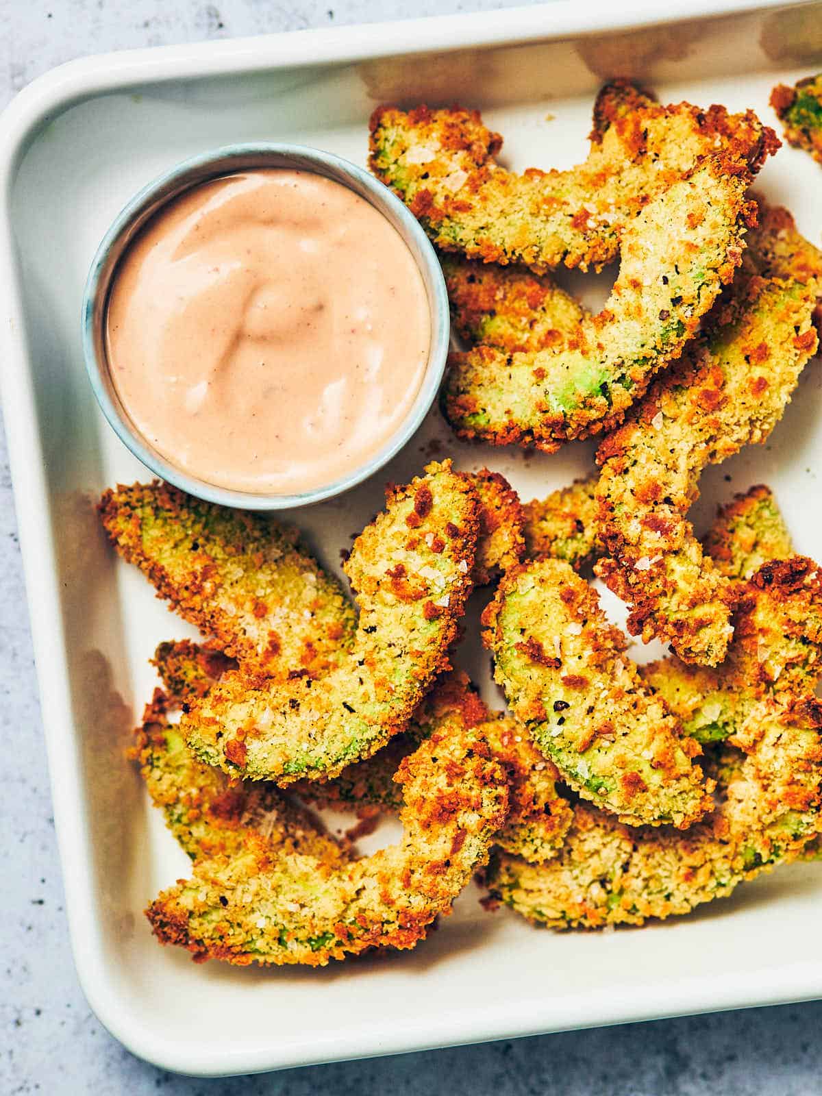 Vegan avocado fries on a tray with dip.