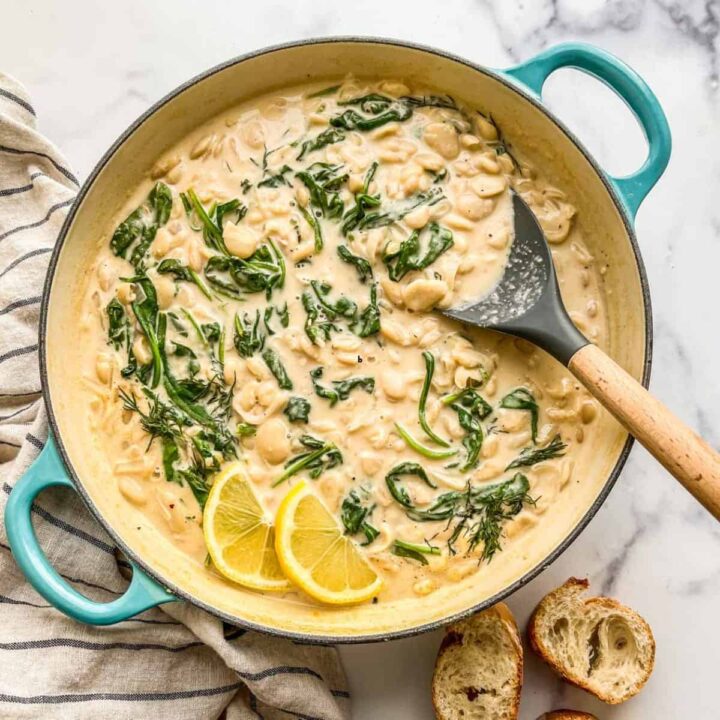 Creamy miso and spinach butter beans in a large pan with a spatula.