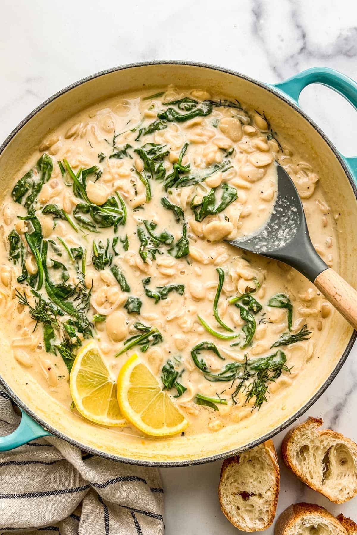 Creamy miso butter beans with spinach in a large pan with a spatula.