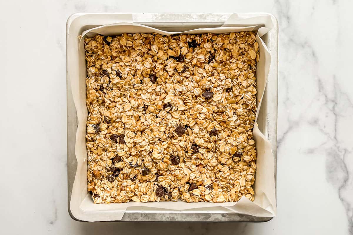 Granola batter added to an 8x8 inch baking pan.