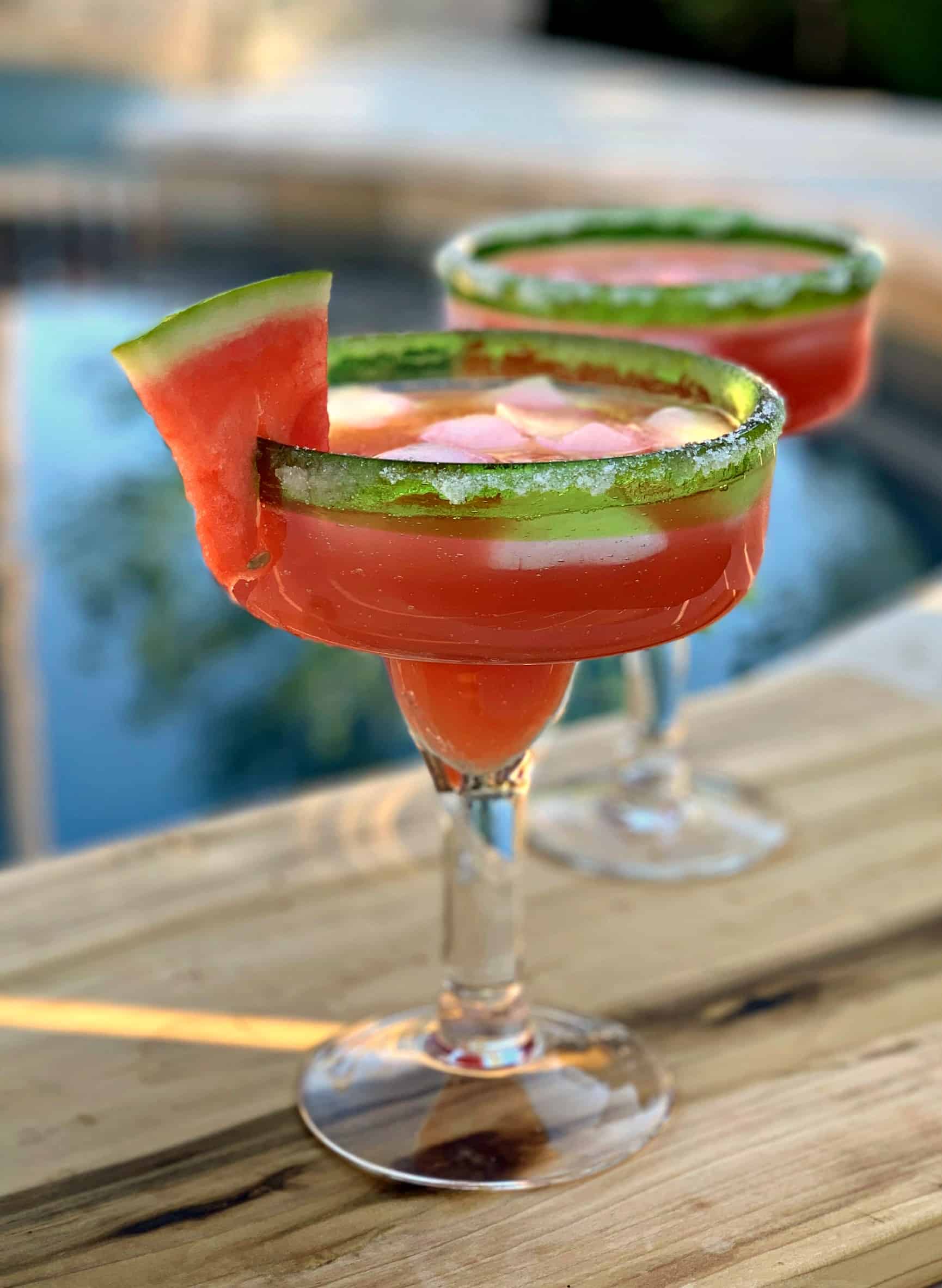 Two glasses of watermelon margarita with a slice of fresh watermelon.