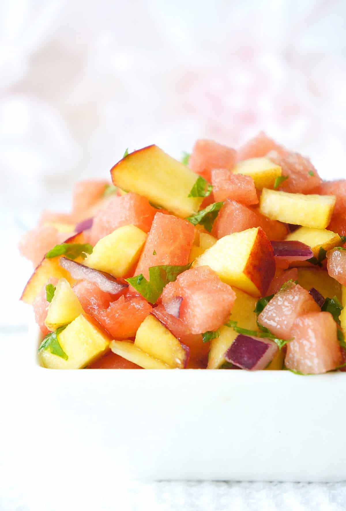 A white bowl with watermelon peach salsa.