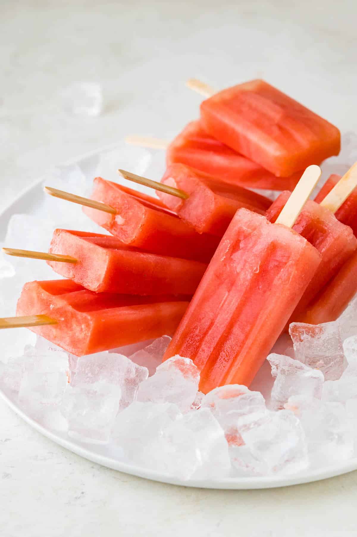 A plate of ice with a stack of watermelon popsicles.