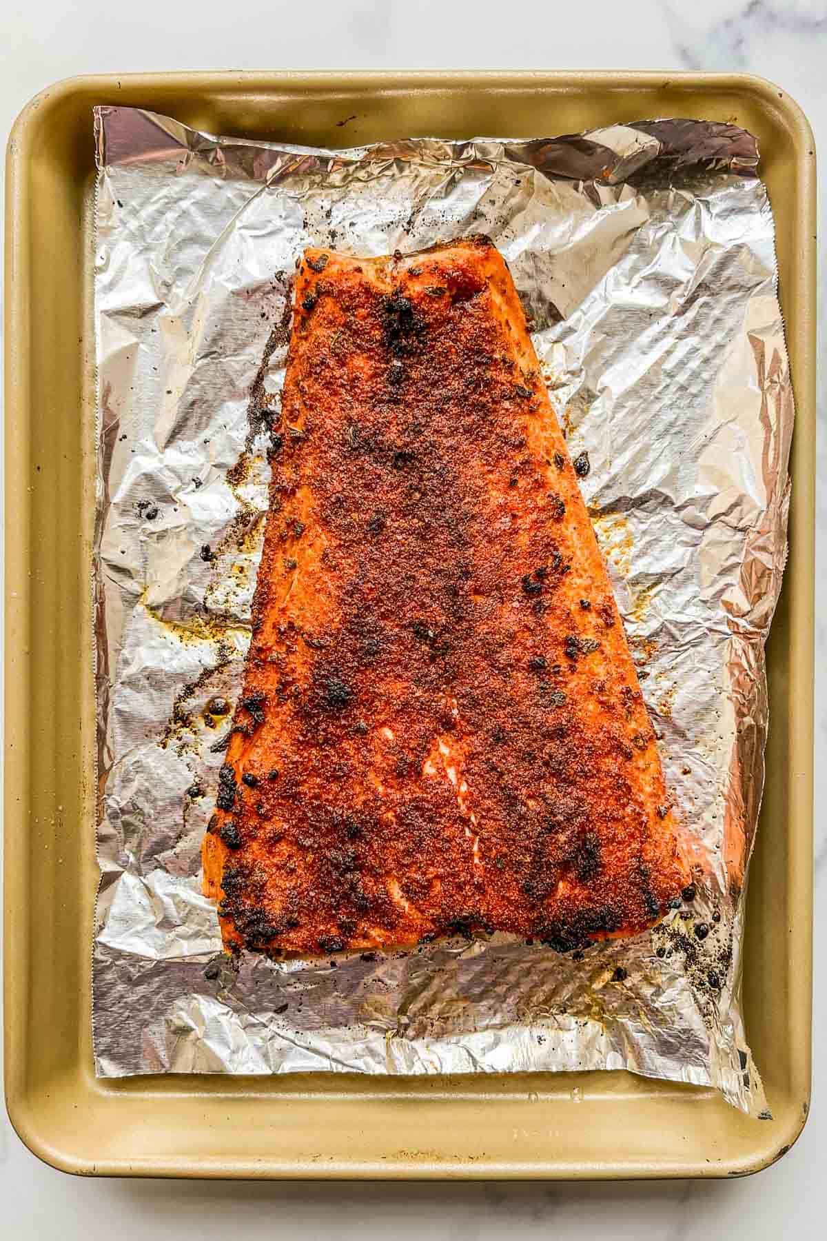 A broiled salmon fillet on a foil lined baking sheet.