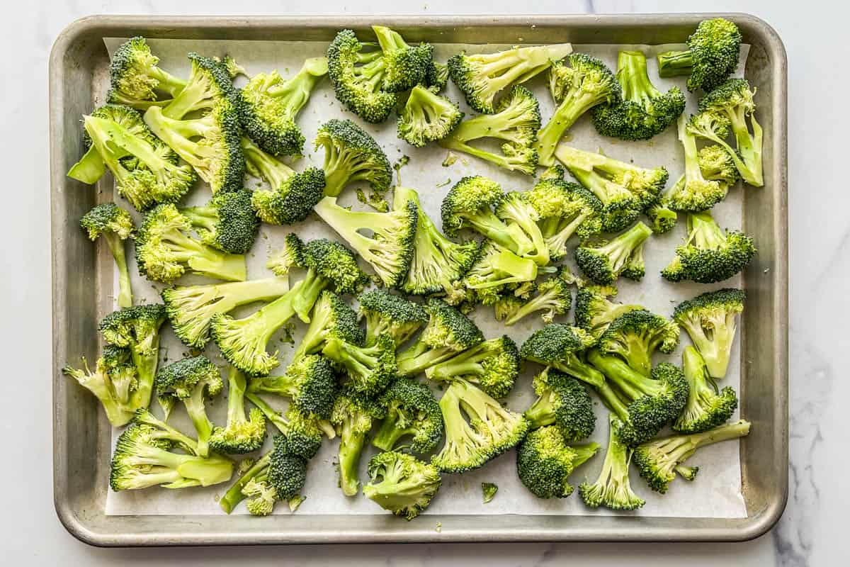 Fresh broccoli florets on a parchment lined sheet pan.