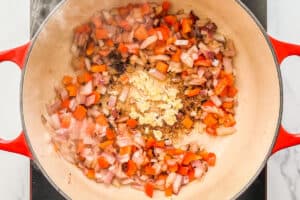 Onions, bell pepper, and minced garlic cooking in a dutch oven.