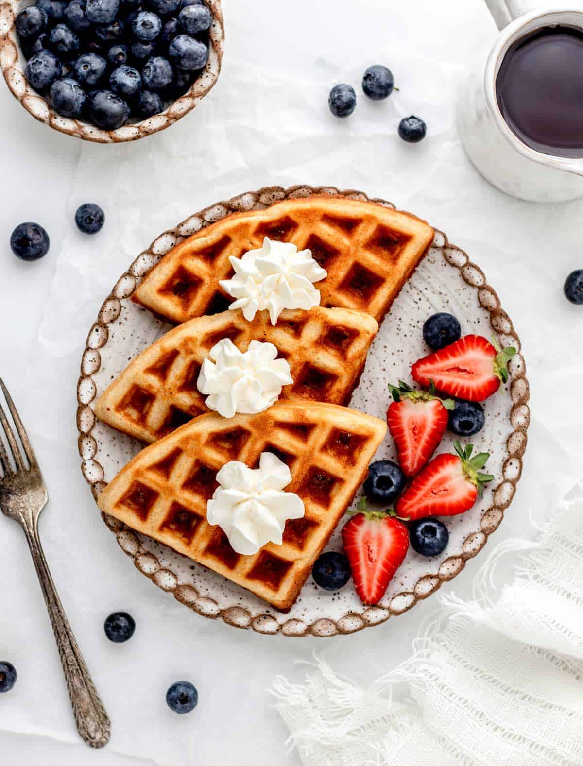 Three almond flour waffles on a plate with berries.