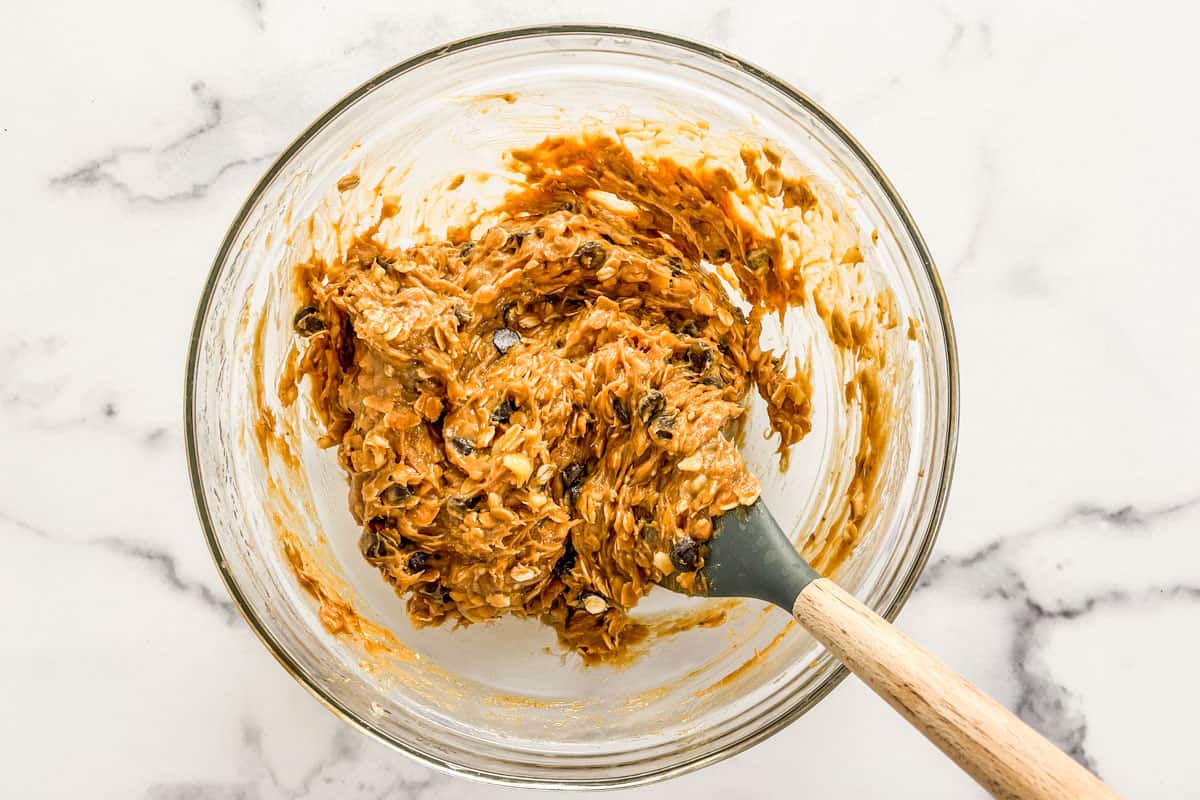 Healthy banana cookie batter in a glass bowl with a spatula.