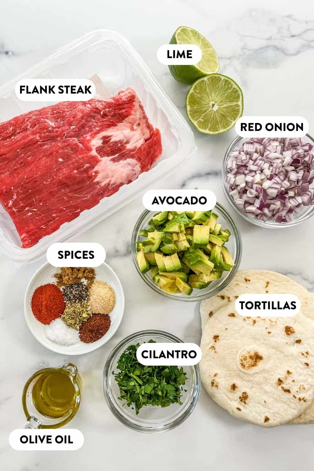 Flank steak taco ingredients on a marble background.