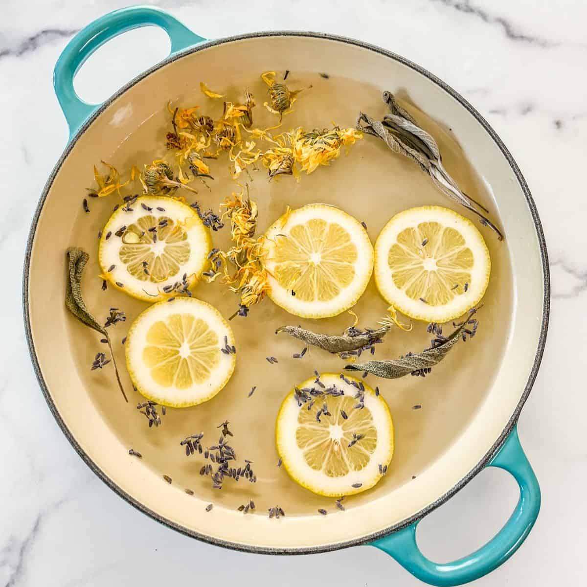 A spring simmer pot with lemons, dried flowers, and dried herbs in a teal skillet.