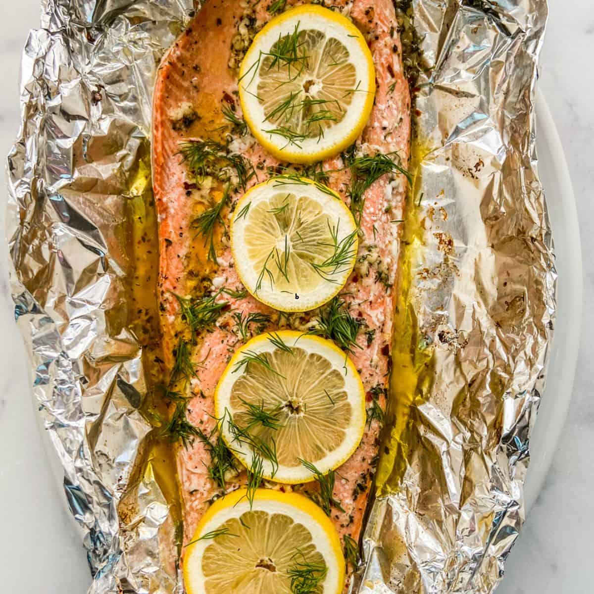 Baked sockeye salmon in foil topped with lemons and fresh herbs.