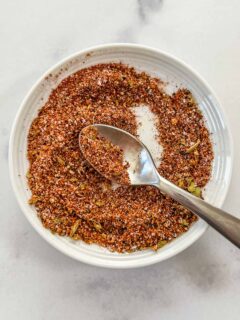 Steak taco seasoning on a small white plate with a silver spoon.