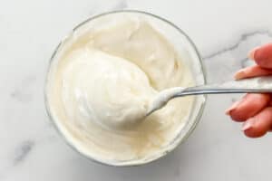 Greek yogurt, honey, and vanilla being mixed in a glass bowl.