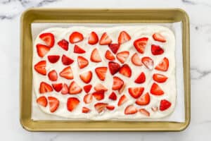 Greek yogurt with sliced strawberries on a parchment lined sheet tray.