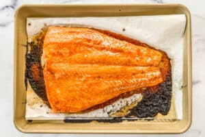 Baked king salmon on a parchment lined sheet pan.