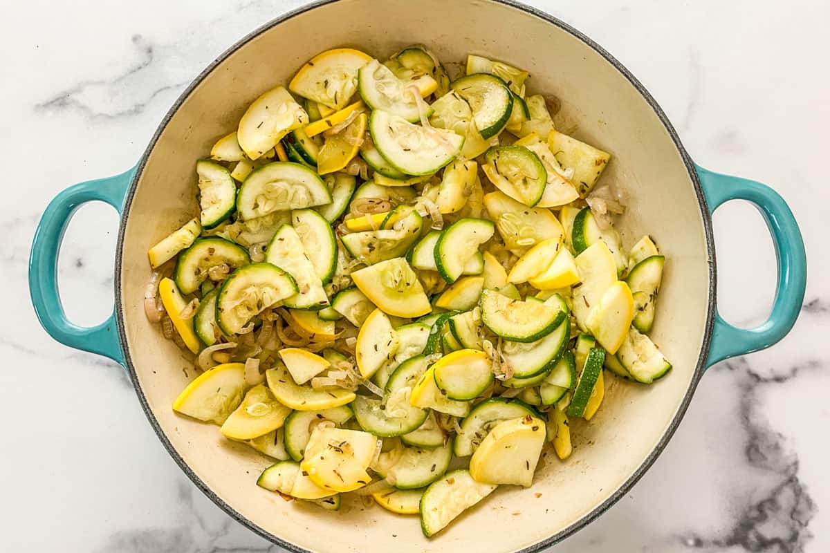 Shallots, yellow squash, and zucchini cooked in a skillet.
