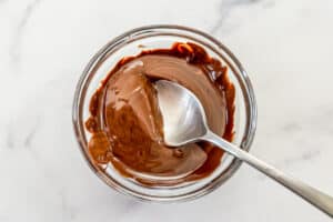 Melted chocolate in a glass bowl with a spoon.