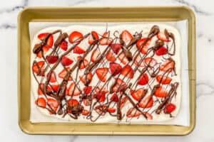Strawberry yogurt bark on a parchment lined sheet pan before going in the freezer.
